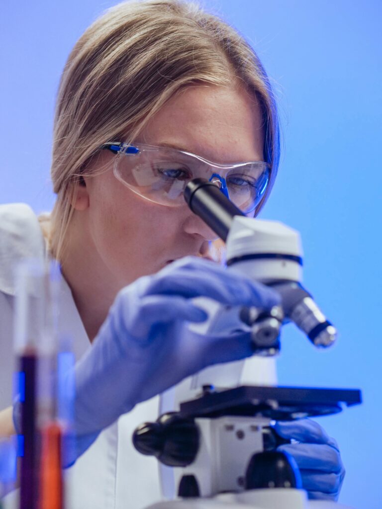 pexels-photo-8325955-8325955 A female scientist wearing goggles and gloves examines a microscope slide in a laboratory.